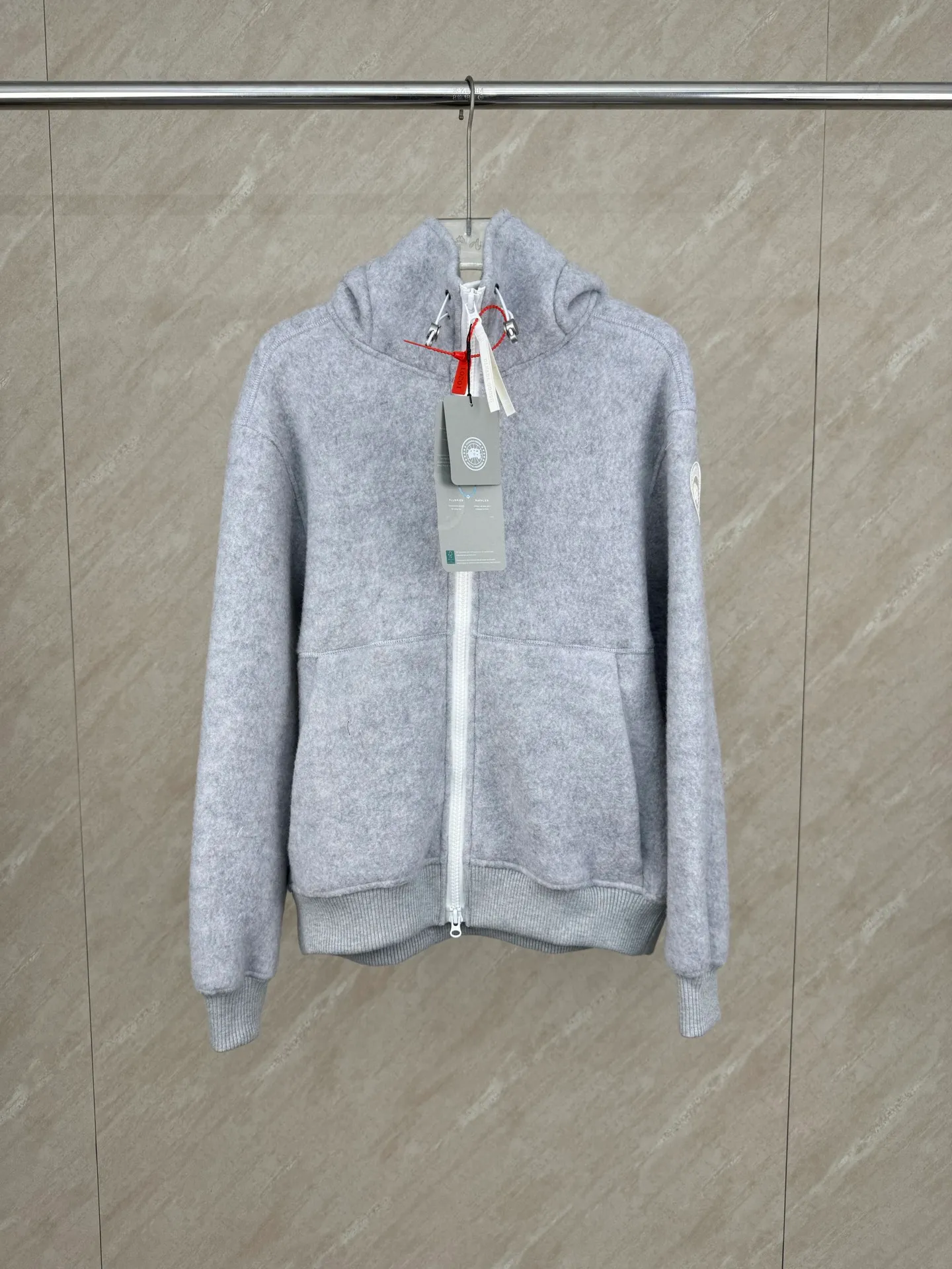 P810 Canada Goos Fleece Badge Hooded Jacket SIZE S/M/L/XL The fabric is made of wool as the main body, with a very small amount of spandex and polyester fiber blended into the wool fleece fabric. The sleeves and hem are closed with 2×2 ribbing. Its strong elasticity can closely fit wrists and waists of different thicknesses, forming an effective 'seal' to prevent cold wind from blowing back. It can still maintain its original shape after repeated stretching and use, and is not easy to loose and deform. And the ribbed cuffs can convey a sense of design and enhance the visual beauty.